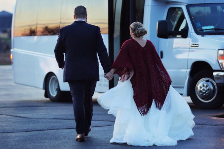 Just married couple walking towards their shuttle bus loaded with guests.